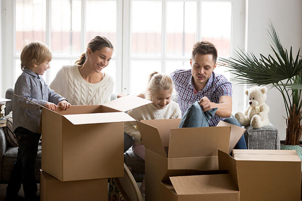a mother, father, son and daughter in the living room opening moving boxes