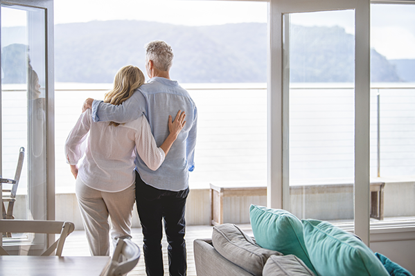 man and woman staring out their balcony towards the ocean view