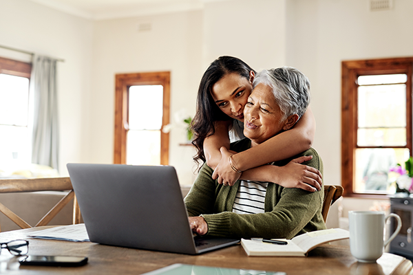 woman hugging mother in front of a laptop
